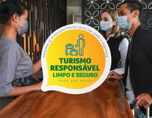 une pancarte sur une table avec des personnes portant des masques dans l'établissement Hotel das Palmeiras, à Paracatu