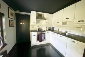 a kitchen with white cabinets and a sink at 17th Century Boutique Getaway in the Countryside in Martin