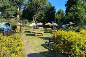 eine Gruppe Picknicktische mit Sonnenschirmen in einem Park in der Unterkunft 17th Century Boutique Getaway in the Countryside in Martin + 9 Fotos