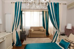 1 dormitorio con cortinas azules, sofá y lámpara de araña en Boutique Vila Paradis en Deva