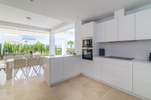 una cocina con armarios blancos y una mesa con sillas. en NEW Luxurious 4-BDRM Villa next to Beach/Golf — La Finca, en Marbella