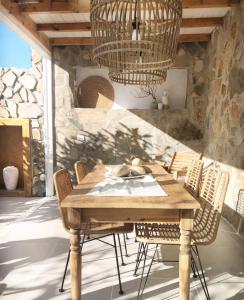 una mesa de madera y sillas en una habitación con una pared de piedra en Casita blanca cerca de Timanfaya, en Tinguatón