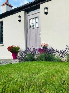 a white house with flowers in the yard at Lavender Cottage - 2 Bedroom Home in Newbridge