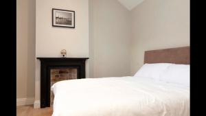 a bedroom with a white bed and a fireplace at Lavender Cottage - 2 Bedroom Home in Newbridge