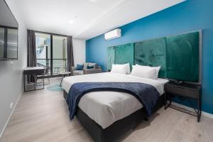 1 dormitorio con 1 cama grande y pared azul en Oros Hotel and Apartments en Oakleigh