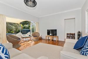 a living room with a white couch and a tv at Somerton - Waipu Holiday Home in Waipu Cove