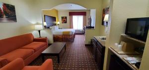 a hotel room with a bed and a couch and a television at Best Western Executive Inn & Suites in Madisonville