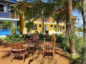 a wooden deck with a table and chairs and a house at Village Acapulco - Itacimirim/BA in Itacimirim