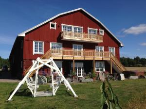 a large red barn with a wooden house at Låsta Gårdshotell in Strängnäs