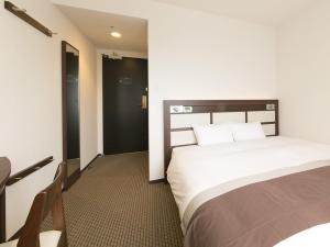 草津市にあるアーバンホテル南草津のベッド2台とテーブルが備わるホテルルームです。
