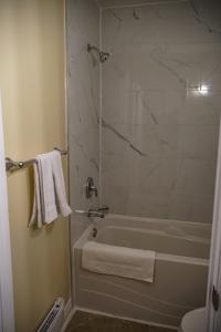 a bathroom with a tub and a shower with white towels at Skyland Motel Inn & Suites in Huntsville