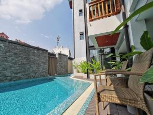 a swimming pool with chairs next to a building at Hotel De Wualai-SHA Extra Plus in Chiang Mai