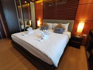 a bedroom with a large bed with towels on it at Hotel De Wualai-SHA Extra Plus in Chiang Mai