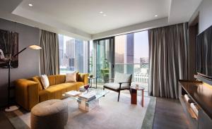 a living room with a yellow couch and a large window at The Hari Hong Kong in Hong Kong