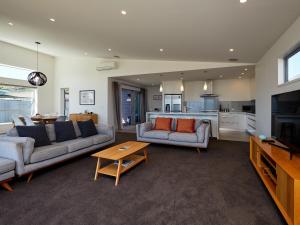 a living room with two couches and a kitchen at The Kaikoura Bach Retreat in Kaikoura