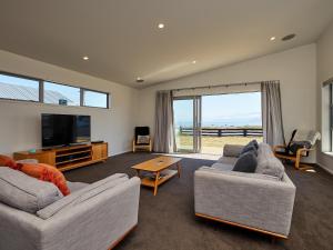a living room with two couches and a flat screen tv at The Kaikoura Bach Retreat in Kaikoura