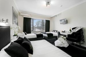 una camera con tre letti e un tavolo con sedie di Airport Hotel Sydney a Sydney