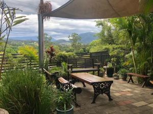 un patio con mesa de madera y bancos con vistas en Grey Gum Lodge, en Nimbin