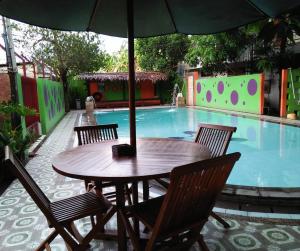 a table with an umbrella next to a swimming pool at Hotel Pesona Merak in Merak