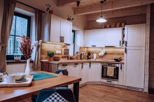 cocina con armarios blancos y mesa de madera en Chata BlueBerry, en Demänovská Dolina