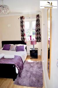 ダゲナムにある2 Bedroom Apartment at Dagenham , Adonai Serviced Accommodation, Free WiFi and Parkingのベッドルーム1室(ベッド1台、紫の敷物付)