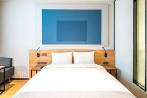 een slaapkamer met een bed met een blauw schilderij aan de muur bij Ibis Ambassador Suwon in Suwon