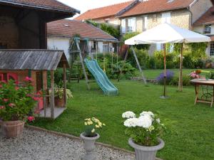 patio trasero con parque infantil con tobogán y sombrilla en Les Célestines, en Lavannes