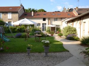un jardín con mesa y sombrilla en Les Célestines, en Lavannes