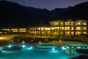 un grande edificio con una grande piscina di notte di Mountain Glory Forest Resort a Pokhara