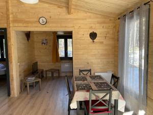 a dining room with a table and a clock on the wall at Parc R&eacute;sidentiel de Loisir : Le Loup Blanc du Riou in Barcelonnette