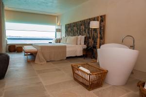 a bedroom with a bed and a tub in a room at Port Royal Villas and Spa - Adults Only in Kolymbia