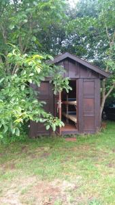 a brown shed with a open door in the grass at Treene Camp Horn in Esperstoft