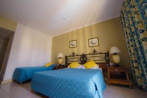 a bedroom with two beds with blue sheets and yellow pillows at Topaz Hotel in St Paul's Bay