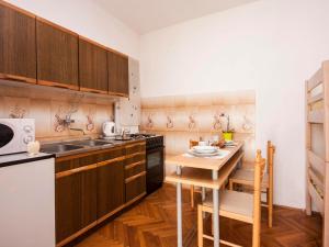 a kitchen with wooden cabinets and a small table at Apartments Tanfara in Brodarica