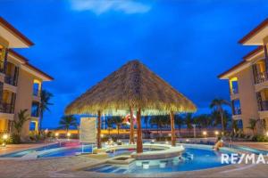 un complexe avec un parasol et une piscine dans l'établissement 777J Beachfront Luxury Condo 3 BR/2.5BA Near SJO - Jaco Beach, à Jacó