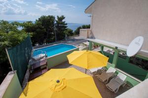 un patio con 2 ombrelloni gialli e una piscina di Apartments Fortuna 3427 a Lokva Rogoznica
