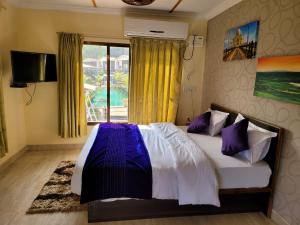 a bedroom with a bed with purple pillows and a window at THE NIHAL RESORT in Mahabaleshwar