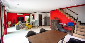 sala de estar con paredes rojas, mesa y sillas en 4poolvillas, en Norte de Pattaya
