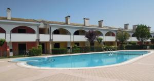 a swimming pool in front of a building at Residence Leopardi - Gemini in Bibione