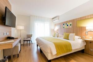 a bedroom with a bed and a desk and a television at Hôtel Hélios in Juan-les-Pins