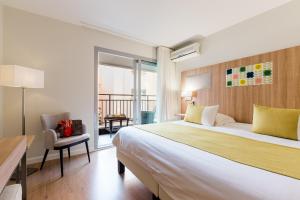 a hotel room with a large bed and a balcony at Hôtel Hélios in Juan-les-Pins