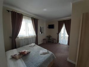 a bedroom with a bed and two large windows at Pensiunea Alessia in Piatra Neamţ