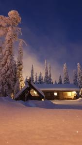una cabaña en la nieve con árboles nevados en Ruka Inn, en Ruka