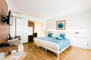 a bedroom with a bed with blue pillows at Hôtel Hélios in Juan-les-Pins