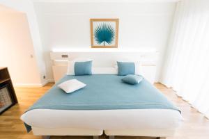 a bedroom with a large bed with blue pillows at Hôtel Hélios in Juan-les-Pins