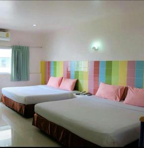 dwa łóżka w pokoju z kolorową ścianą w obiekcie Center Mansion at Hatyai w mieście Hat Yai