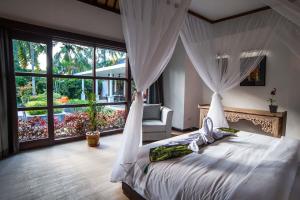 a bedroom with a white bed with a canopy at Villa Matha Ubud - Renewal in Ubud