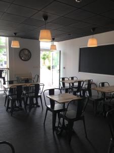 a dining room with tables and chairs and a projection screen at L'ETAPE DE SANTENAY in Santenay
