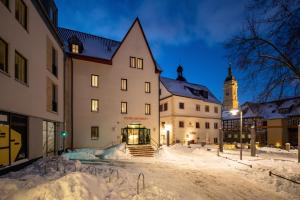 a building in the snow with a clock tower in the background at Hotel am Markt in Eisenach
