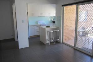 a kitchen with white cabinets and bar stools in it at Cronulla Beach Elanora Gardens in Cronulla
